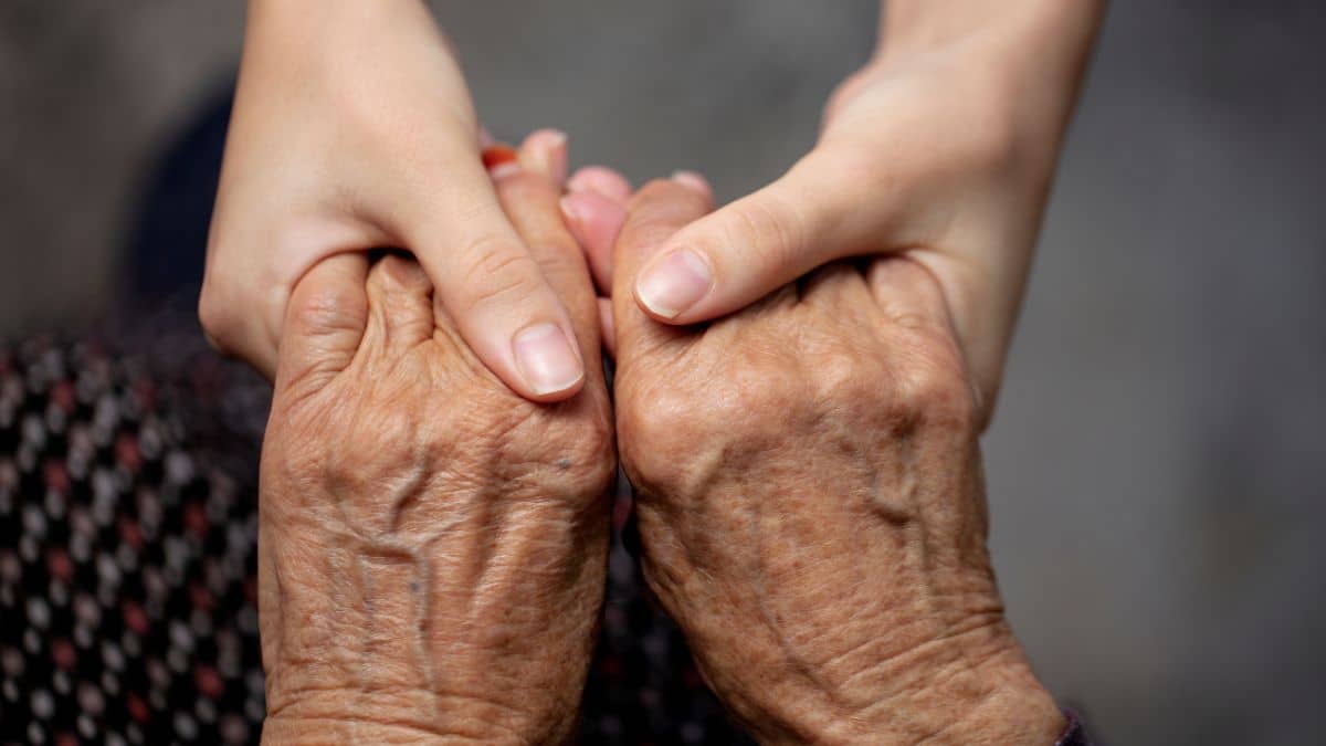 Mãos de um idoso sendo seguradas por outra pessoa simbolizam os desafios do envelhecimento e do diagnóstico tardio do autismo no Brasil